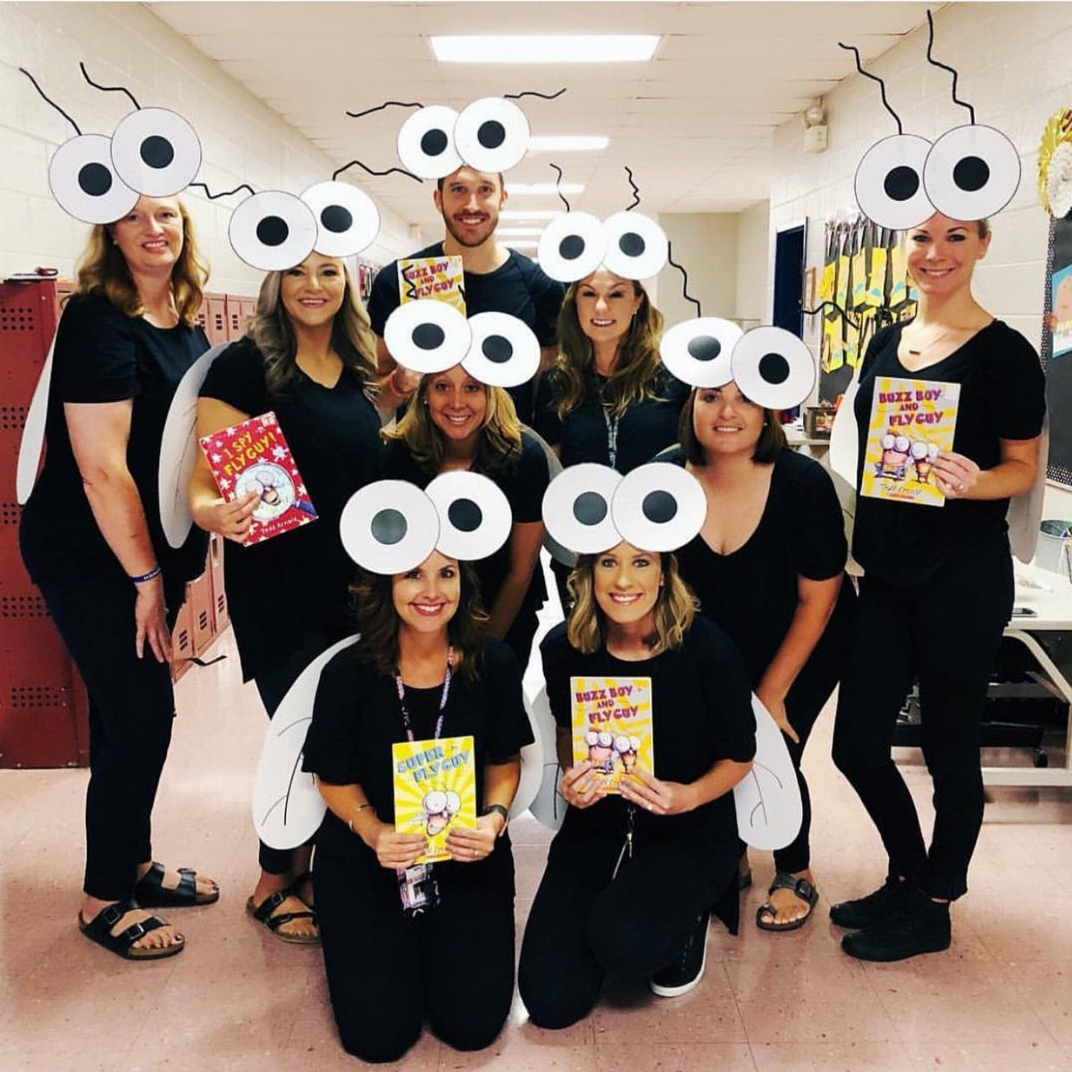 Group of teachers dressed as flies with wings and googly eye headbands.