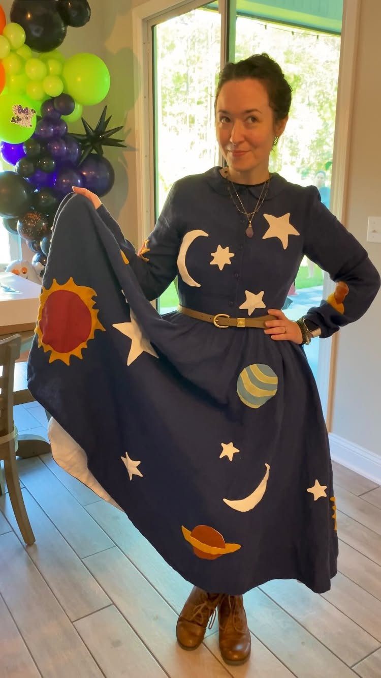 Woman wearing a navy blue space-themed dress with stars and planets for Halloween.