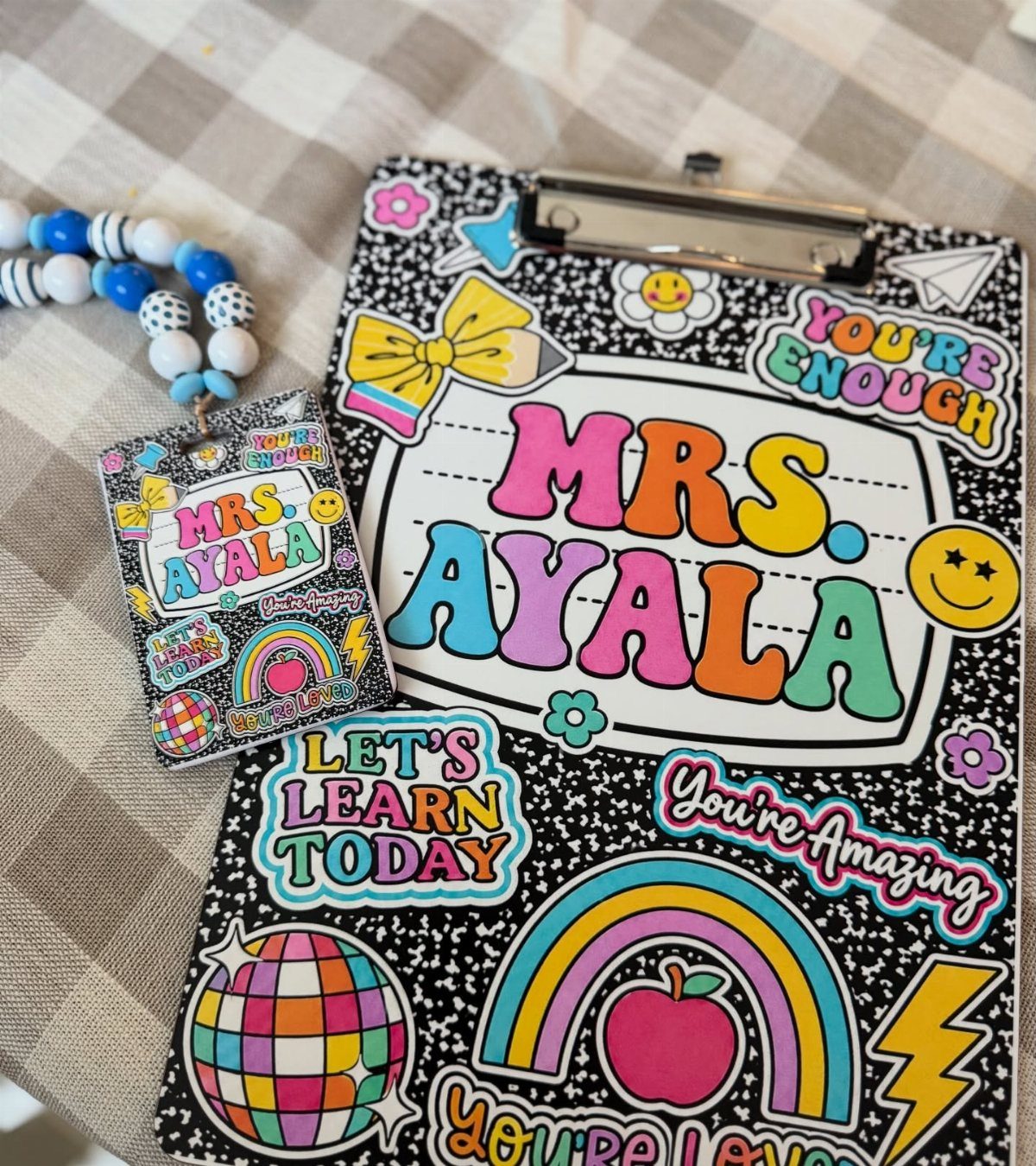 Personalized clipboard and badge reel for Mrs. Ayala with colorful educational stickers.