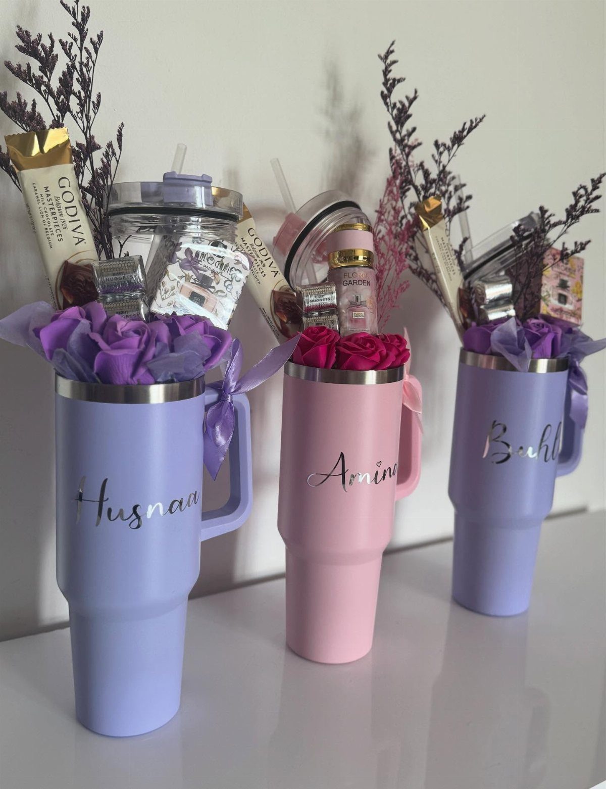 Personalized colorful tumblers filled with chocolates and flowers as curated gift sets.