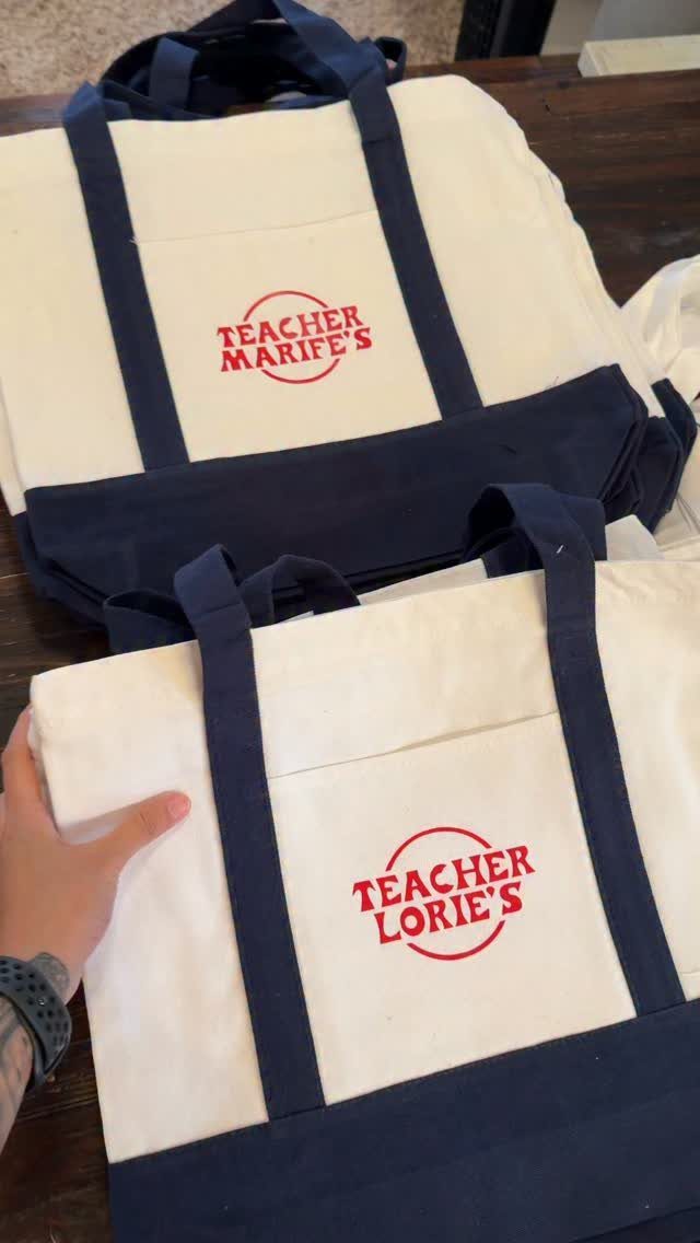 Personalized canvas tote bags for teachers with red text and navy blue straps.
