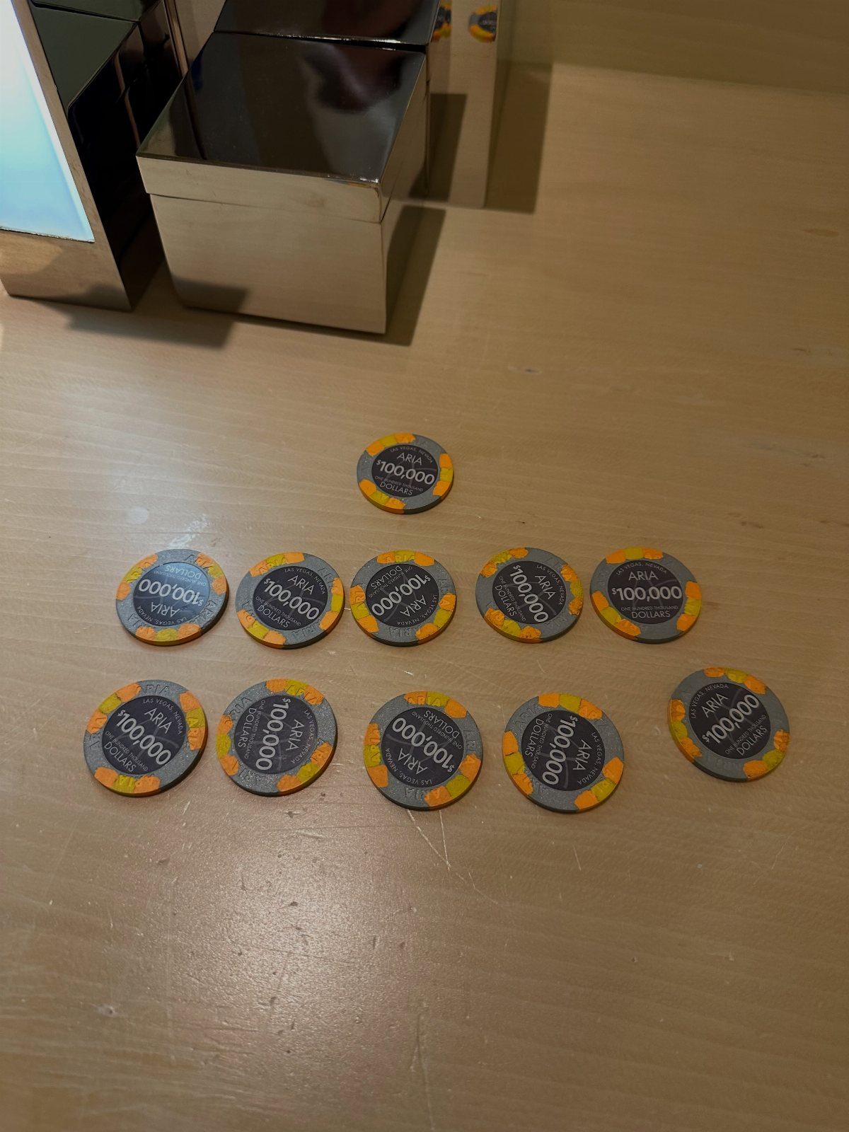 Grey poker chips with yellow edges arranged on a light wooden table