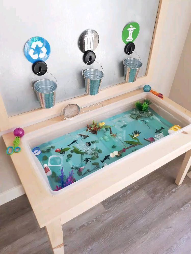 Water sensory bin in a wooden table filled with blue water and toys