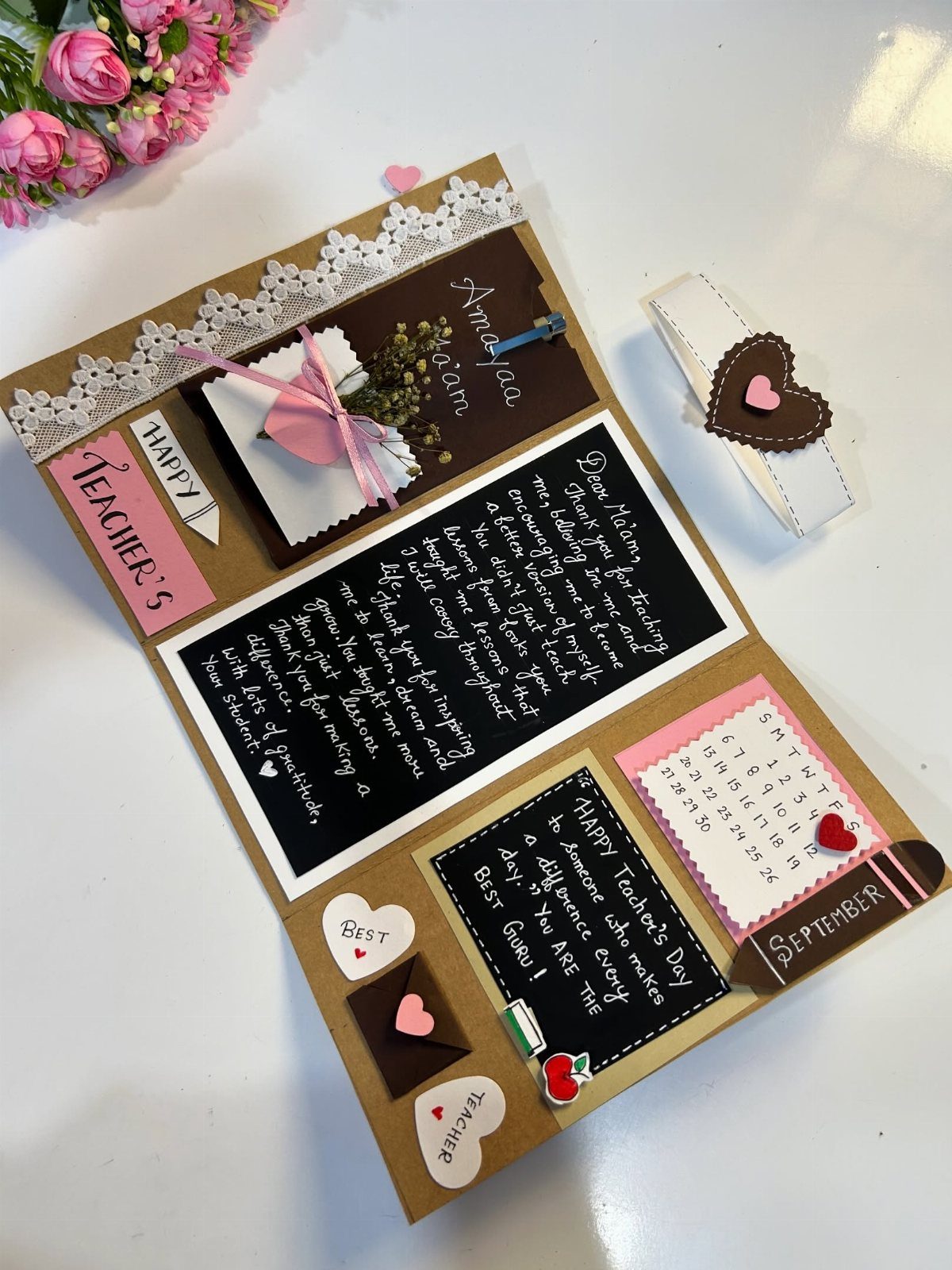 Handmade teacher's day card with chalkboard notes, a calendar, and pink decorations.