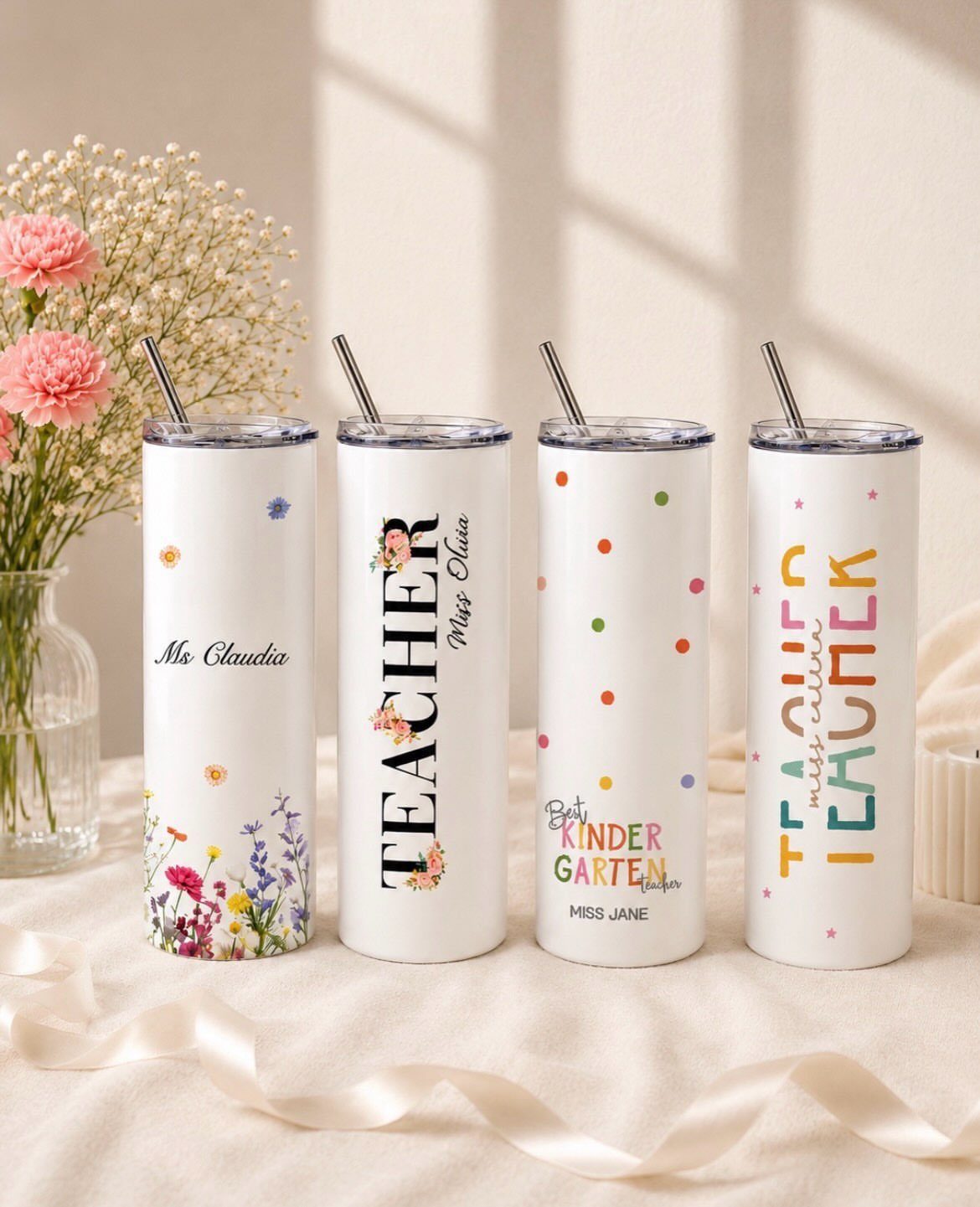 Four personalized white tumblers with teacher-themed designs and names on a white surface.